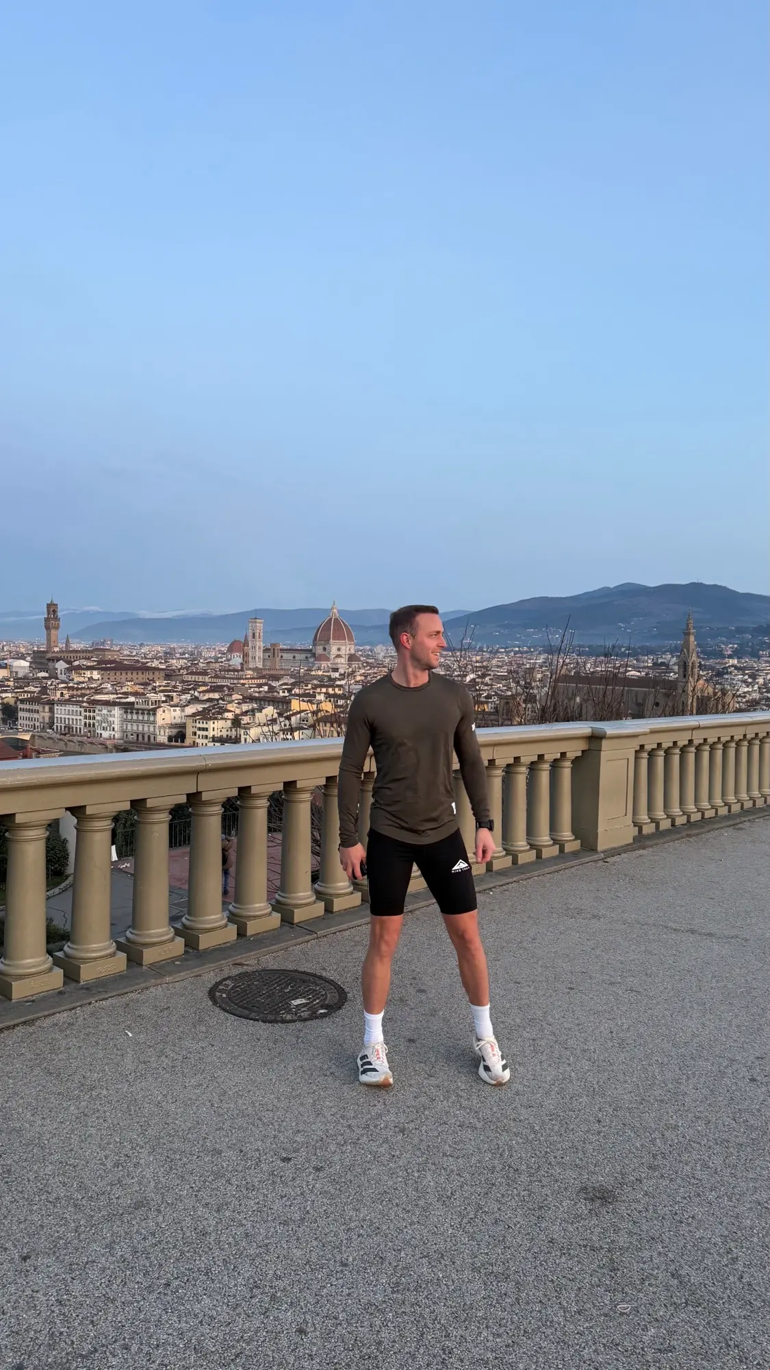 Dom Carter in running kit on a terrace above Florence, with the Duomo behind him