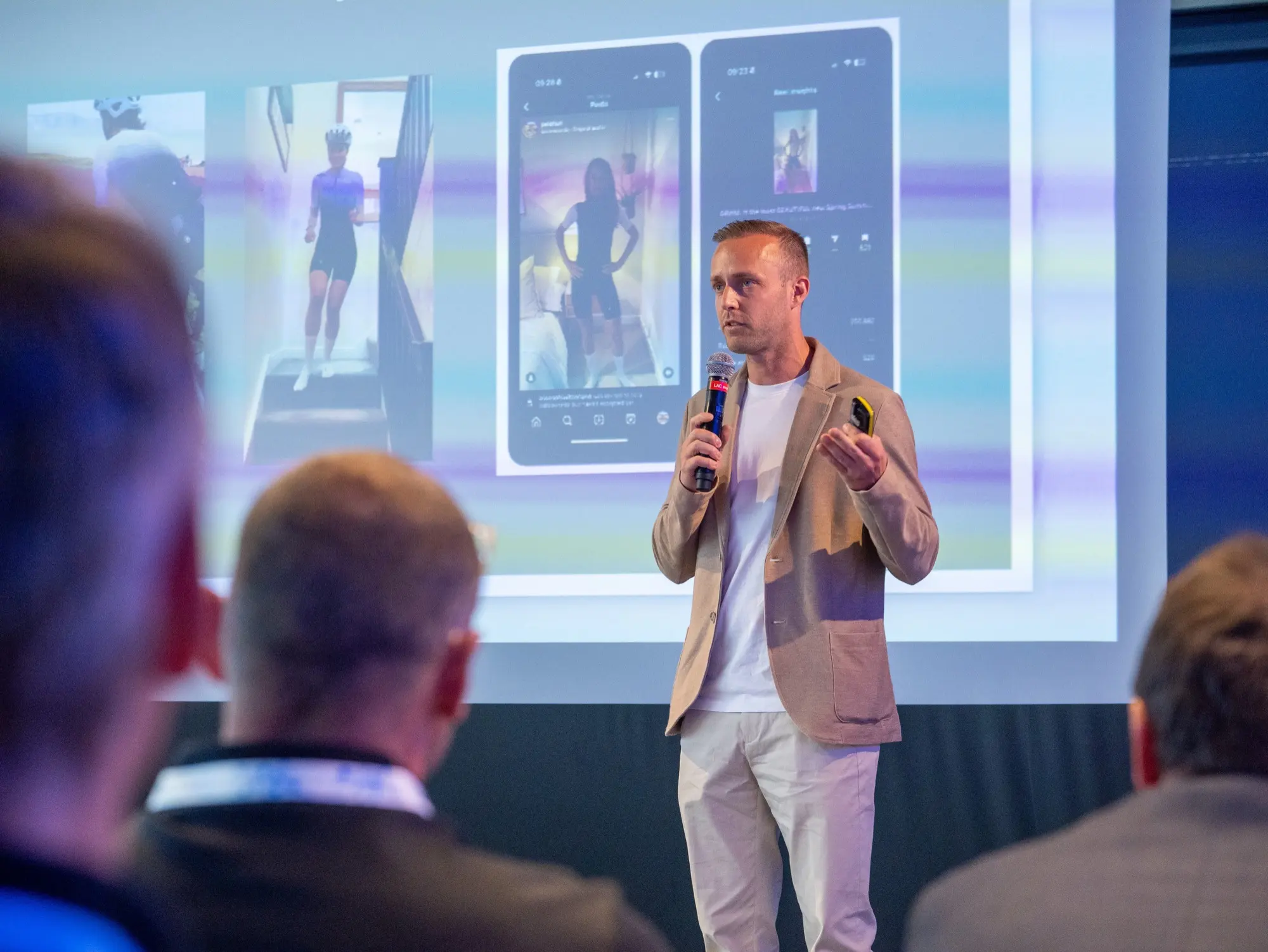 Dom Carter on stage in front of a screen showing phone screenshots of Instagram reels